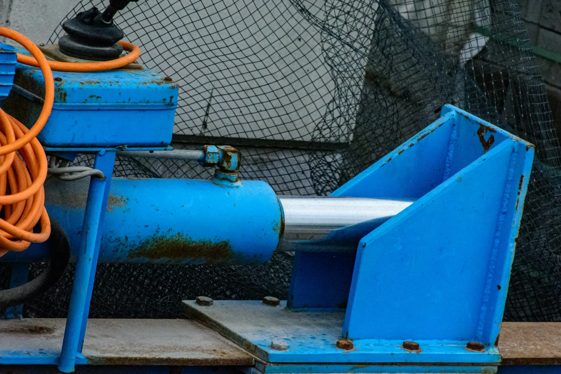 Blue industrial machinery with orange cable and netting